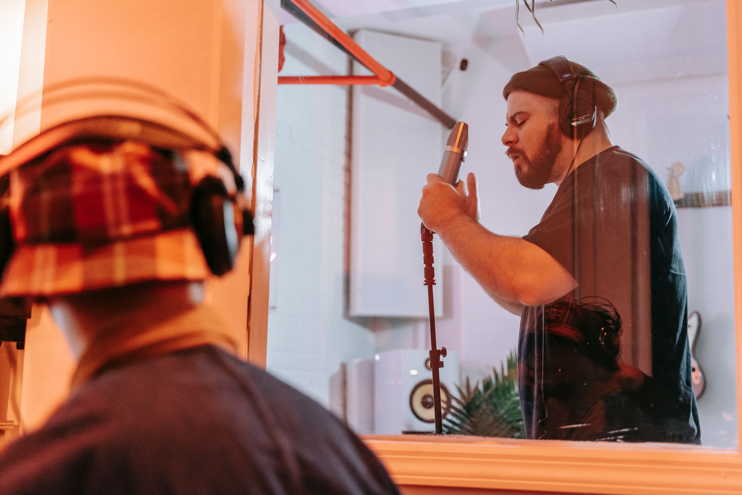 Musician performing in a modern recording studio with a condenser microphone.