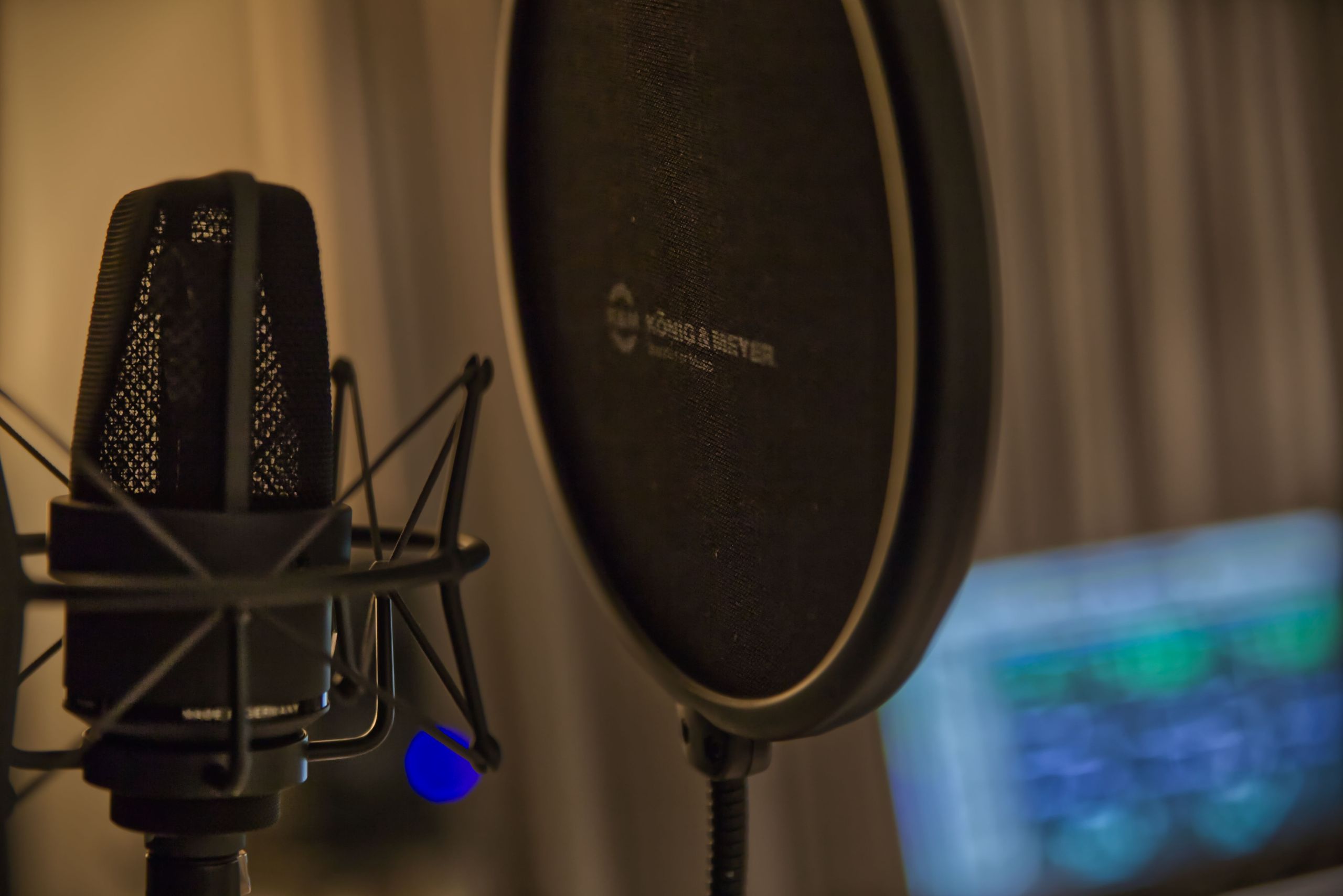 Close-up of a studio microphone and pop filter in a recording environment.